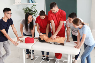 instructor demonstrating CPR on mannequin at first aid training course