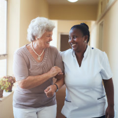 caregiver and senior woman walking together through a corridor